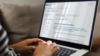 Hands typing on a laptop with code visible on the screen.