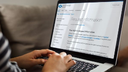 Hands typing on a laptop with code visible on the screen.