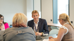 Four people seated around a table in an office, engaged in a professional discussion.