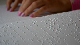 Hands touching textured white paper, possibly reading Braille.