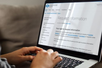 Person typing on a laptop showing information about requesting data from the Scottish Government.