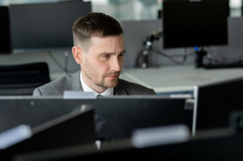 Person working at a computer with multiple monitors in an office setting.