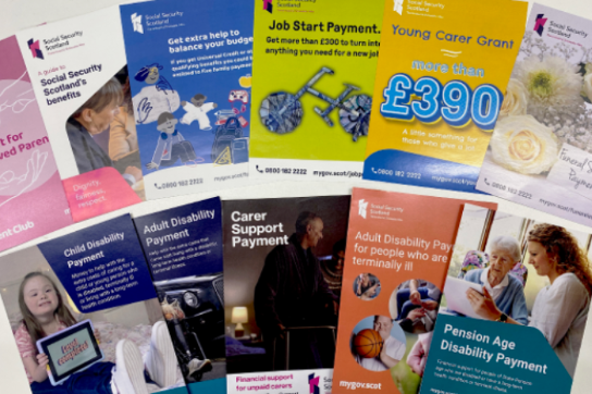 A selection of Social Security Scotland marketing materials lying on a table