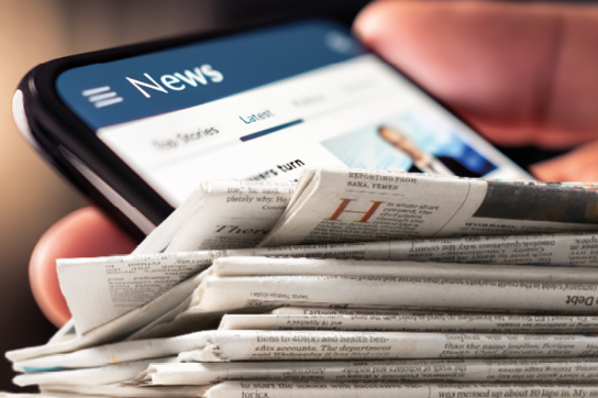 A mobile phone and a pile of newspapers