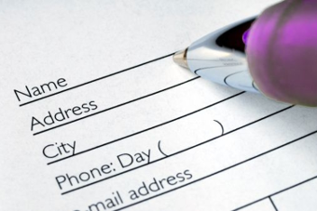Close-up of a form with fields for personal details and a pen positioned above it.