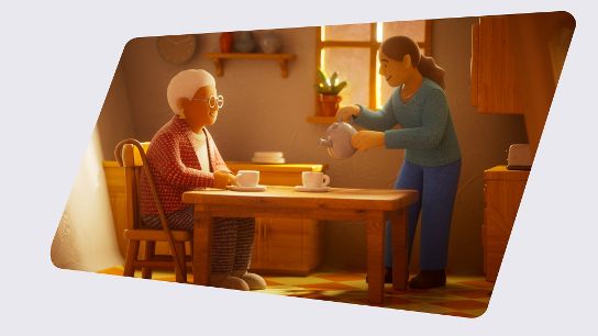 An older adult sits at a kitchen table while another person pours tea into their cup