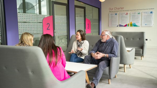 Four people seated around a table in an informal meeting area.