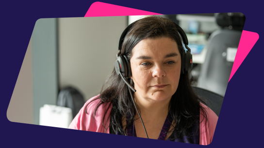 Person wearing a headset, seated at a desk in an office environment.