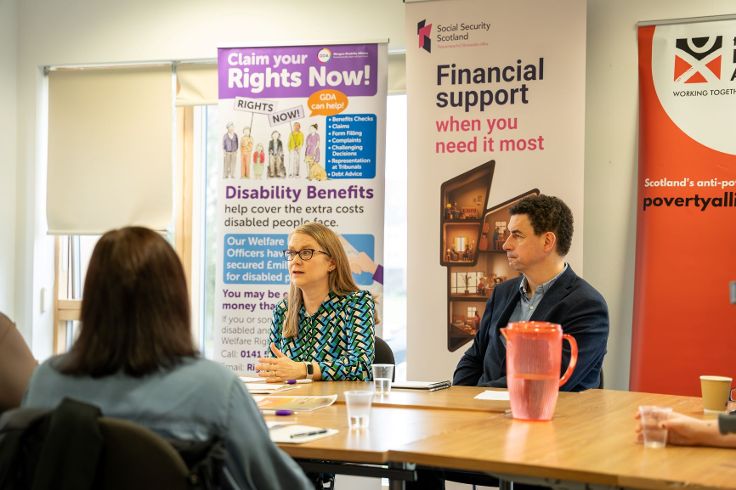 Social Justice secretary chats with people around a board table