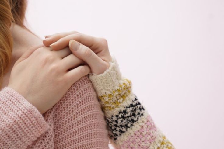 Photograph of a person's hand on another person's shoulder.