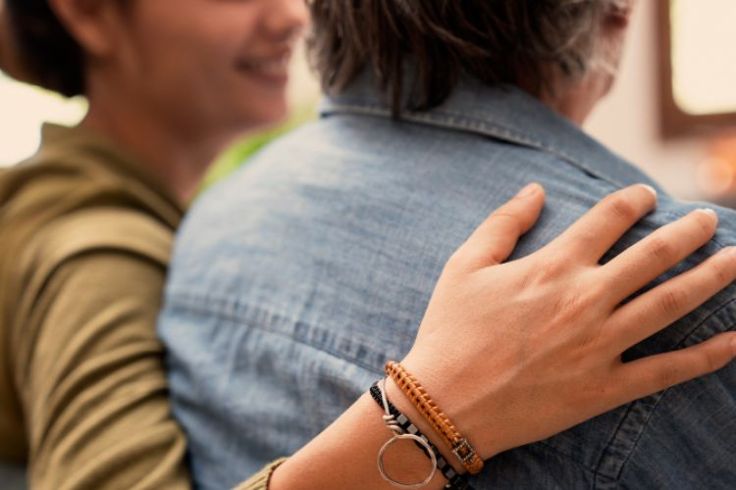 A photograph of a person's hand on another person's shoulder.