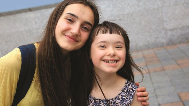 Image of a young carer with their sibling, smiling at the camera.