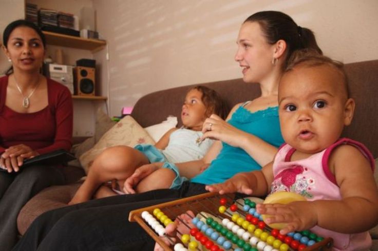 People including young children sit on a living room couch