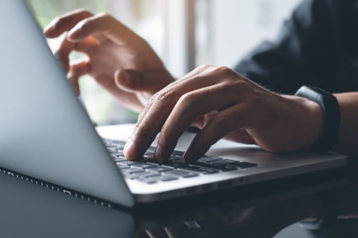 Hands typing on a laptop