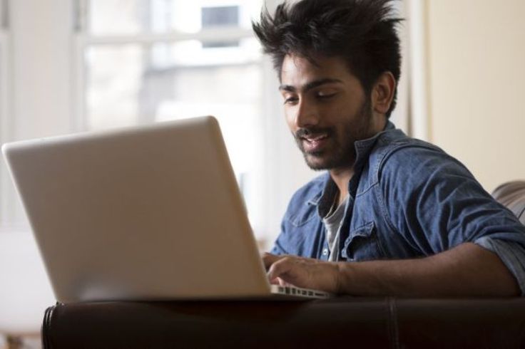 A man sat on an armchair using a laptop
