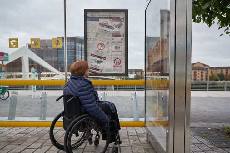 Woman in a wheelchair at a bus stop