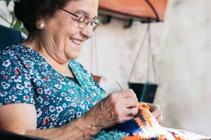 An older woman sat in a chair knitting.