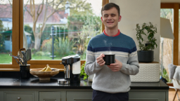 Person standing in a kitchen holding a mug