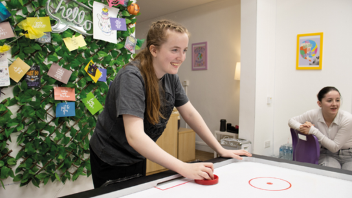 Person playing air hockey in a room decorated with colourful notes and artwork on the wall.