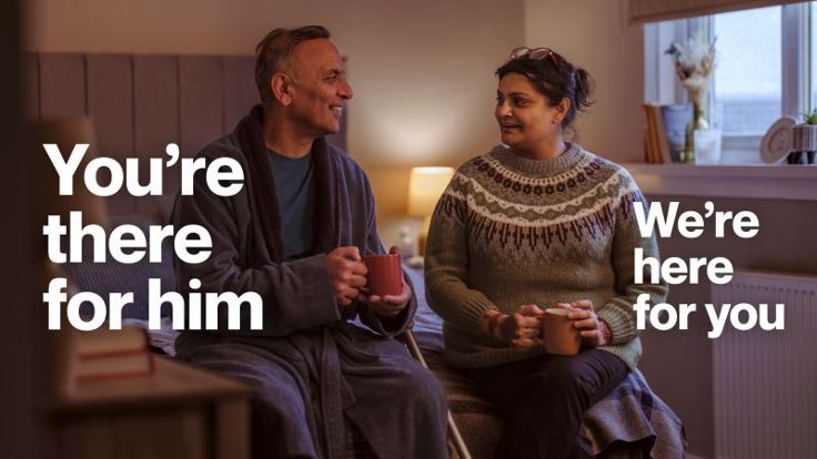 Two people sat on a bed. The caption reads 'You're there for him, we're here for you'.