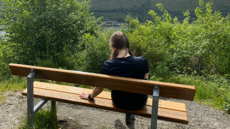 Girl sitting with an empty space next to her on a bench