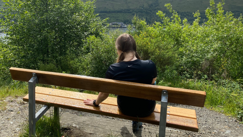 Girl sitting with an empty space next to her on a bench