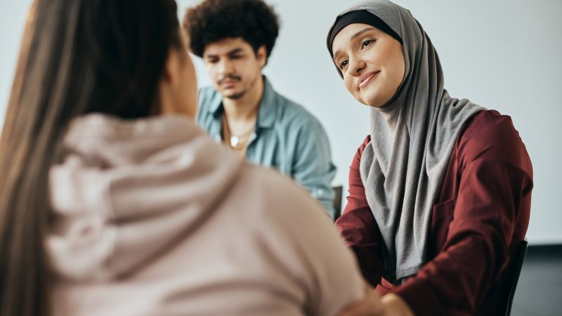 Person wearing a hijab consoling a younger person