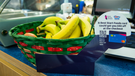 Basket containing fruit at a supermarket check out with Best Start Foods marketing.