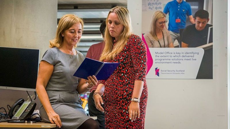 Two colleagues looking at a notebook