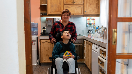 A person is in a kitchen with a child who is in a wheelchair