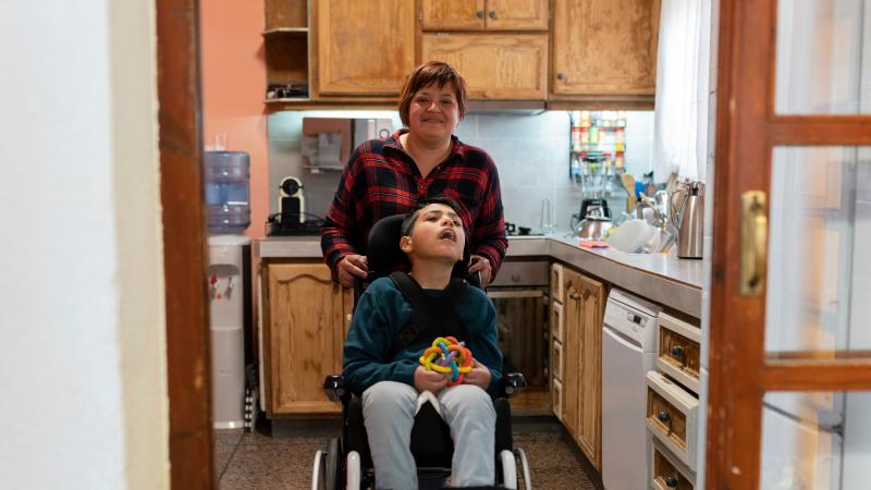 A person is in a kitchen with a child who is in a wheelchair