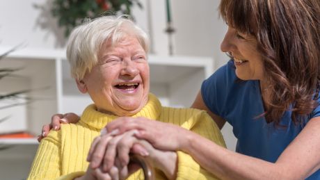 Carer holding hands and smiling with elderly woman