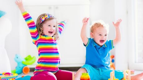 Two young children throwing their hands in the air and smiling