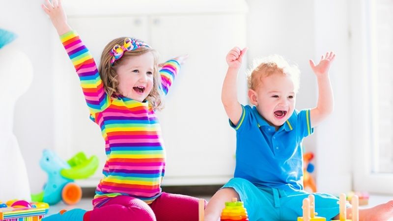 Two young children waving their hands in the air