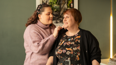 A person is helping their parent put on a cardigan