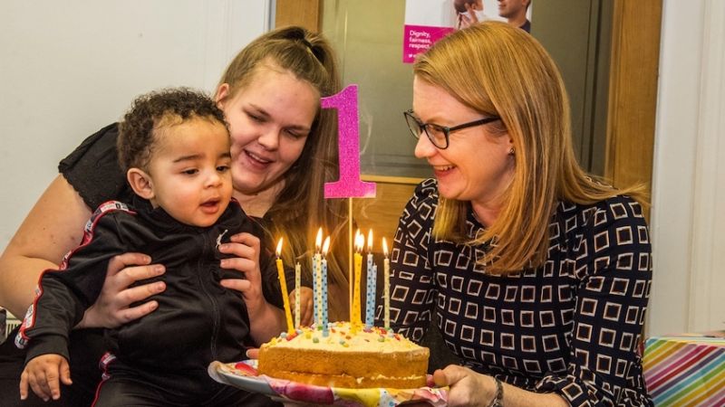 Cabinet Secretary, Shirley Anne Somerville holds a cake as a young child prepares to blow out the candles
