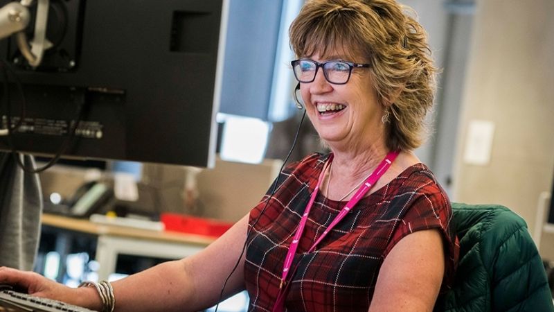 Colleague sitting with a headset on smiling at a computer screen