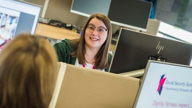 Woman sitting a desk smiling at a colleague sitting across from her