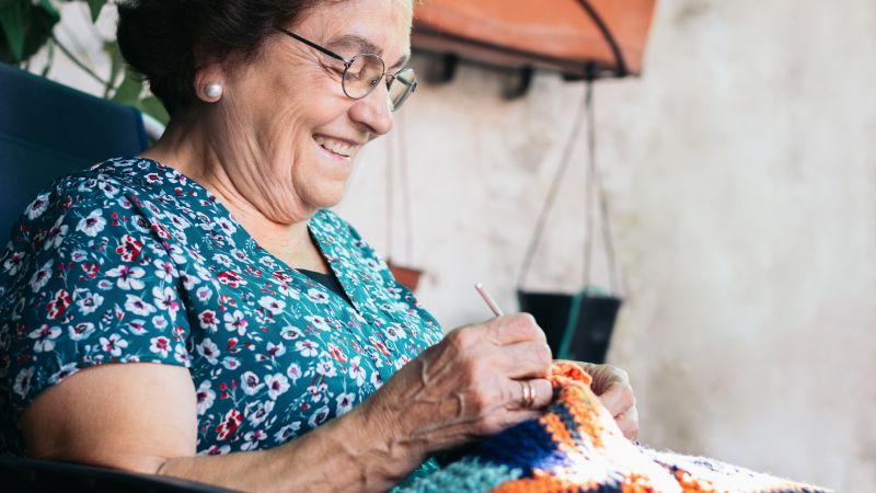Pensioner smiling and knitting