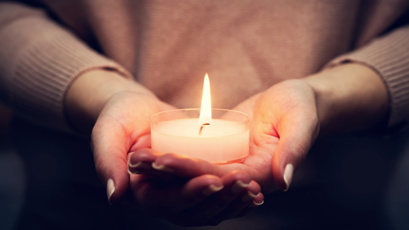 A person holding a small candle.