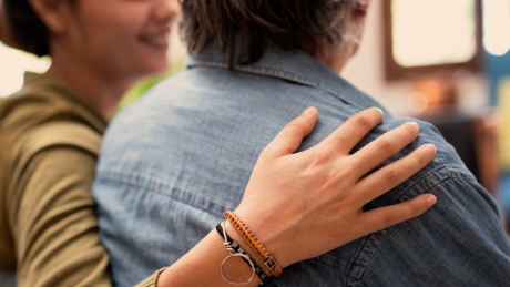 A close up of a hand placed on someone's shoulder