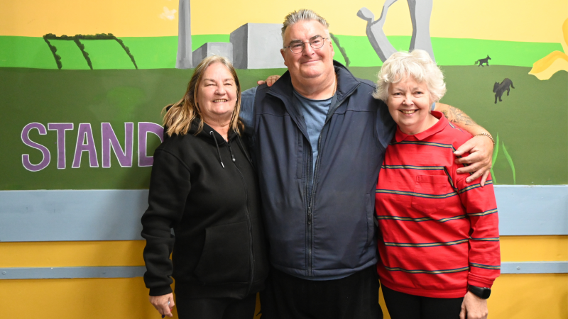 Three people smile warmly at the camera