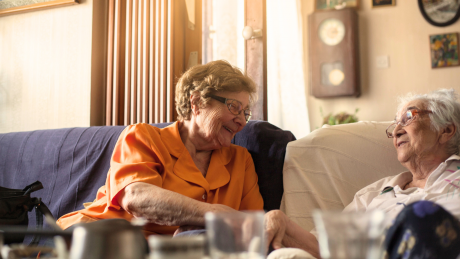 Two people of pension age chat on the sofa