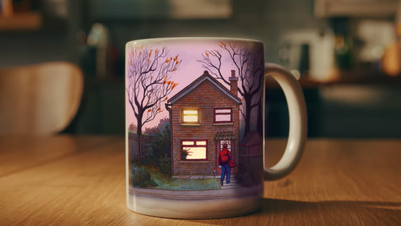 A mug with a house on it is on a kitchen table