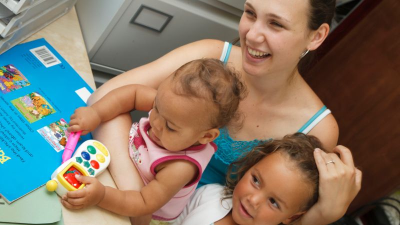 Woman holding a baby and young child