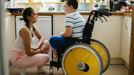 young woman talking to boy in wheelchair