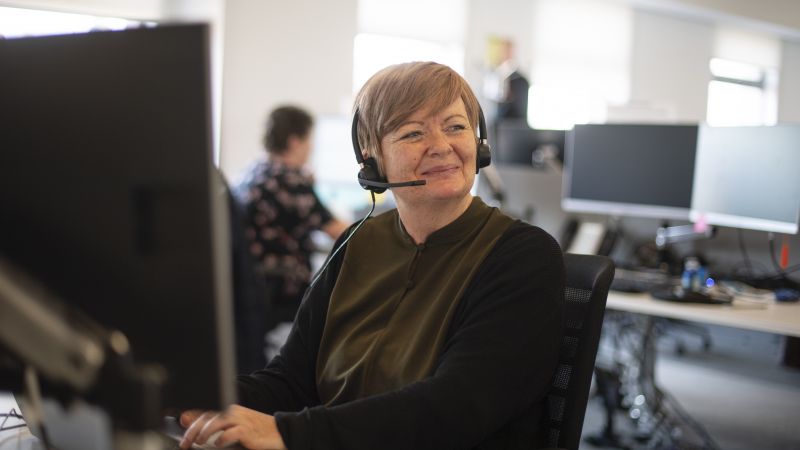 A staff member at a computer wearing a headset