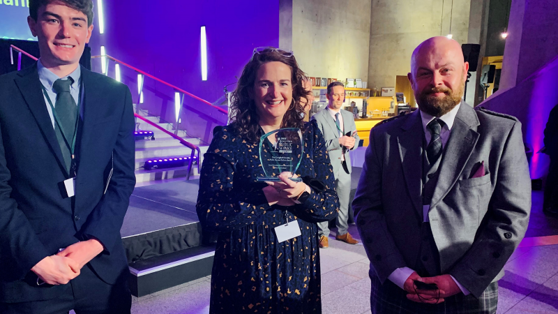 Two males and a female who is holding the award at the ceremony