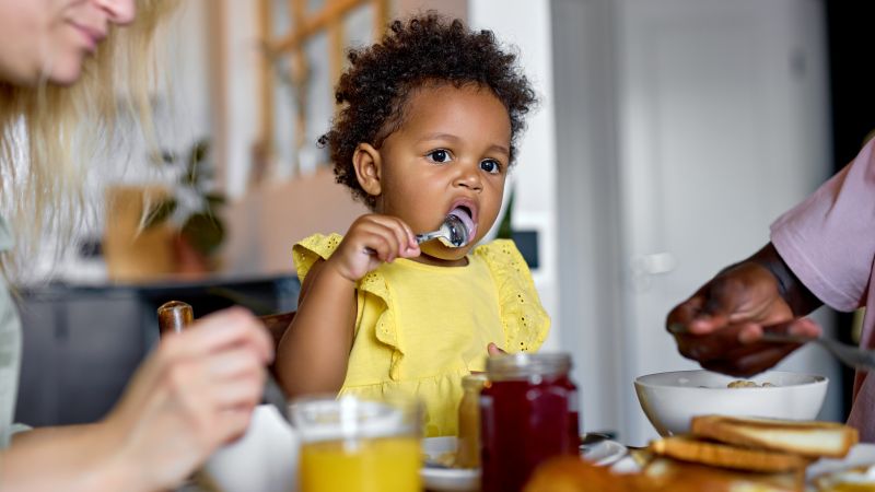 Small child eating from a spoon at table