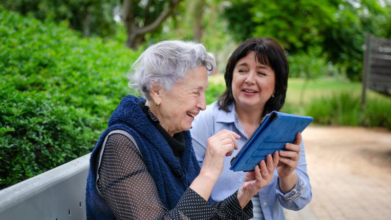 A person sitting with another person using a tablet